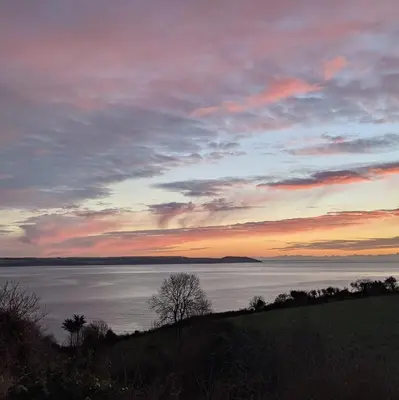 a sunset over a large body of water at Seaside Holiday Cottage Near Beach in Charlestown