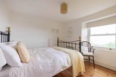 a bedroom with a bed and a window and a chair at Seaside Holiday Cottage Near Beach in Charlestown