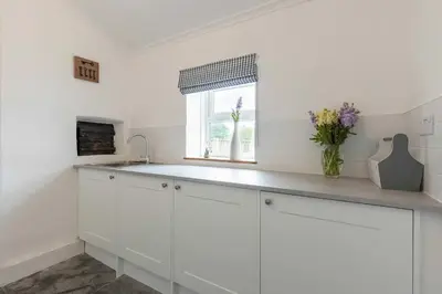 a white kitchen with a sink and a window at Seaside Holiday Cottage Near Beach in Charlestown