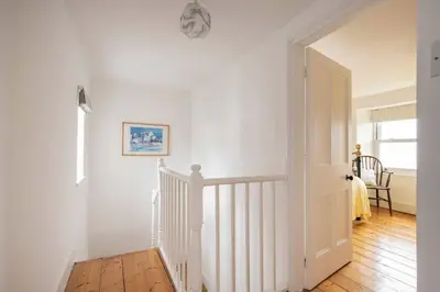 a white hallway with a white door and a staircase at Seaside Holiday Cottage Near Beach in Charlestown