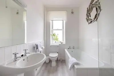 a white bathroom with a sink and a tub and a toilet at Seaside Holiday Cottage Near Beach in Charlestown