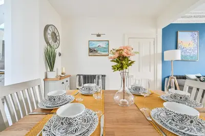 a dining room with a table with plates and flowers at Luxury Georgian Townhouse Moments from the Harbour in Looe