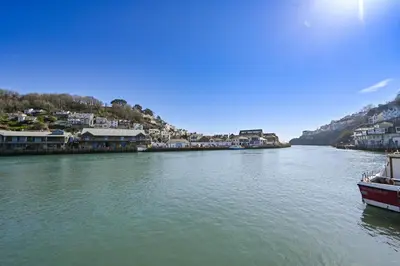a boat is docked on a river with houses at Luxury Georgian Townhouse Moments from the Harbour in Looe