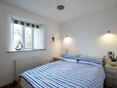 a bedroom with a bed with blue and white stripes at Stable Cottage in Port Isaac