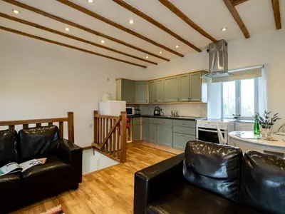 a living room with a couch and a kitchen at Stable Cottage in Port Isaac
