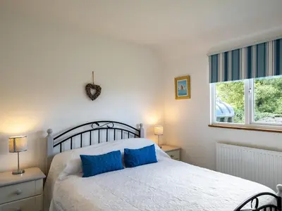 a bedroom with a bed with blue pillows on it at Atlantic Lodge in Port Isaac