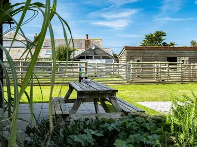 a wooden picnic table in front of a fence at Atlantic Lodge in Port Isaac