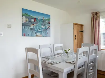 a white dining room with a white table and white chairs at Gull Lodge in Port Isaac