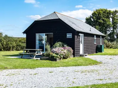a black shed with a picnic table in front of it at Harbour Lodge in Port Isaac