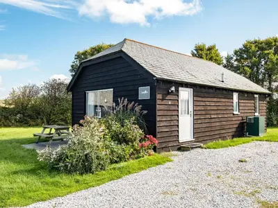 a black shed with a picnic table in front of it at Campion Lodge in Port Isaac