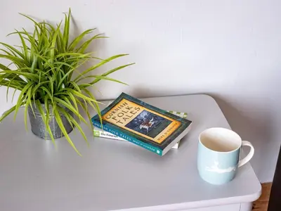 a book and a cup of coffee on a table with a plant at Campion Lodge in Port Isaac