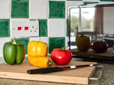 a cutting board with two peppers and a knife at Campion Lodge in Port Isaac