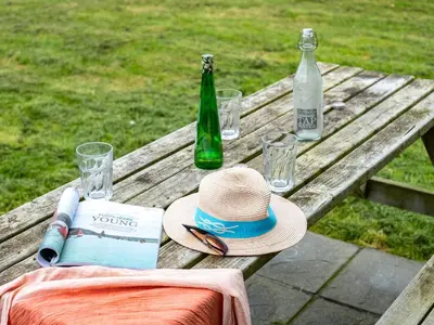 a picnic table with two bottles and a hat and a book at Campion Lodge in Port Isaac