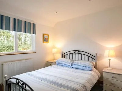 a bedroom with a bed and two lamps and a window at Campion Lodge in Port Isaac