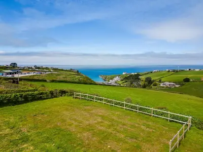 an open field with the ocean in the background at Puffin Lodge in Port Isaac