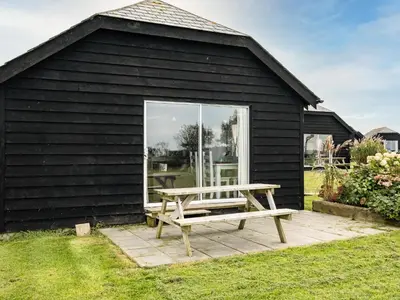 a picnic bench in front of a black building at Dolphin Lodge in Port Isaac