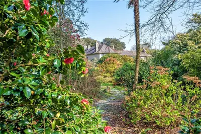 a path through a garden with a house in the background at Wodehouse in Falmouth