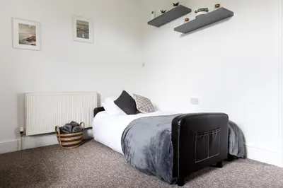 a bedroom with a large bed with white walls at Little Haven in Falmouth