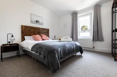 a bedroom with a bed with pink pillows and a window at Little Haven in Falmouth