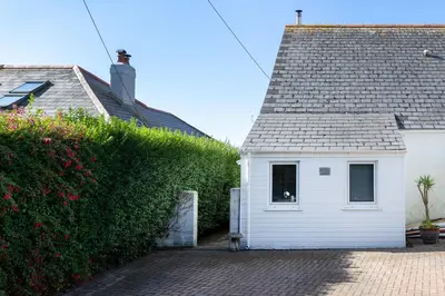 a small white house next to a green hedge at Little Haven in Falmouth