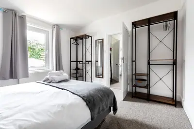 a white bedroom with a large bed and a window at Little Haven in Falmouth