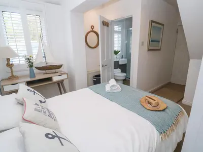 a white bedroom with a bed with a hat on it at Trewartha in Penzance