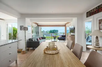 a kitchen and living room with a wooden table and chairs at Trewartha in Penzance