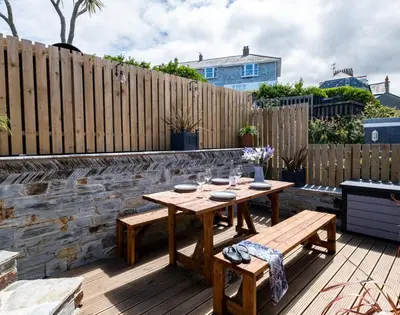 a wooden table and benches on a patio with a fence at Mino Cottage in Port Isaac