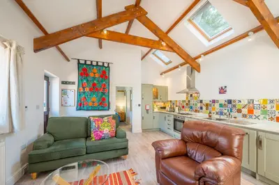 a living room with a couch and a chair at Polrunny Farm Sloe Cottage with a sea view in Boscastle