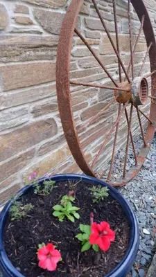 a pot with flowers in it next to a wheel at Polrunny Farm Sloe Cottage with a sea view in Boscastle