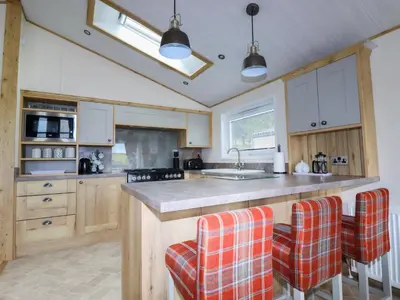 a kitchen with a large island with orange bar stools at Beachcliff in Newquay