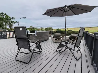 two chairs and an umbrella on a deck at Beachcliff in Newquay