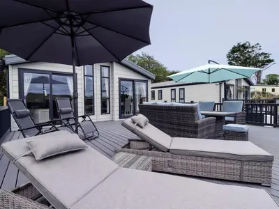 a patio with chairs and umbrellas on a deck at Beachcliff in Newquay