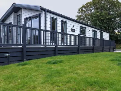 a white house with a black fence in the grass at Beachcliff in Newquay