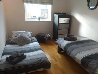 two twin beds in a room with a window at Fistral beach apartment in Newquay