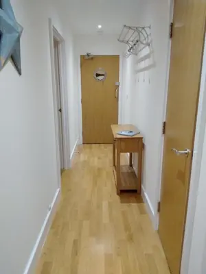 a hallway with a wooden table and a door at Fistral beach apartment in Newquay