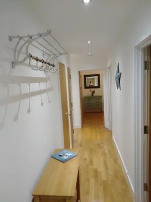 a living room with a wooden table and a hallway at Fistral beach apartment in Newquay