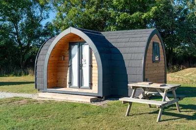 a small shed with a bench and a picnic table at Camping Pods Trevella Holiday Park in Crantock