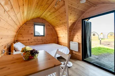 a room with a bed and a table in a cabin at Camping Pods Trevella Holiday Park in Crantock