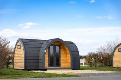 a small house with a black roof and a wooden facade at Camping Pods Trevella Holiday Park in Crantock
