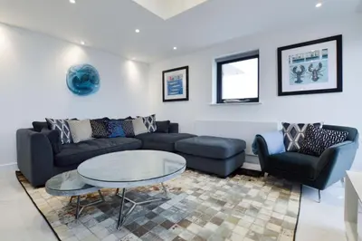 a living room with a couch and a table and chairs at Trevose Penthouse in Newquay