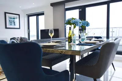 a dining room with a table with chairs and wine glasses at Trevose Penthouse in Newquay