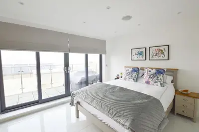 a bedroom with a bed and a large window at Trevose Penthouse in Newquay