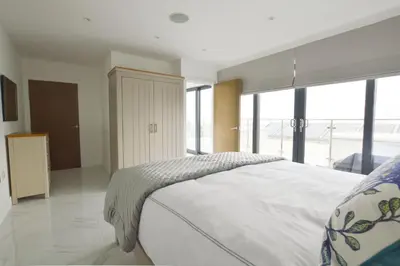 a bedroom with a large bed and large windows at Trevose Penthouse in Newquay