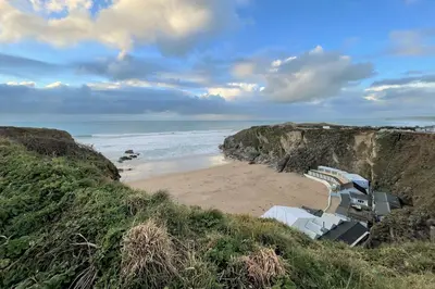 a beach with umbrellas and chairs on a cliff at Trevose Penthouse in Newquay