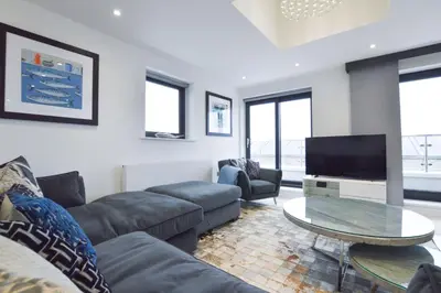 a living room with a couch and a flat screen tv at Trevose Penthouse in Newquay