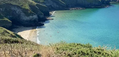 a beach with people on the sand and the water at Polrunny Farm Seaberry Cottage with a sea view and log burner in Boscastle