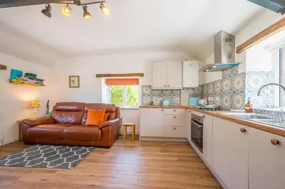 a kitchen with a brown leather couch in a room at Polrunny Farm Seaberry Cottage with a sea view and log burner in Boscastle