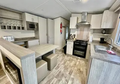 a kitchen with white cabinets and a counter top at Luxury 3 bedroom caravan between Perranporth and Newquay, Cornwall in Newquay