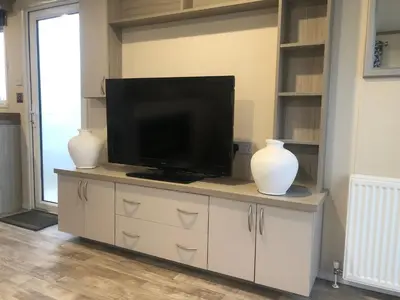 a television on a cabinet with two vases on it at Luxury 3 bedroom caravan between Perranporth and Newquay, Cornwall in Newquay